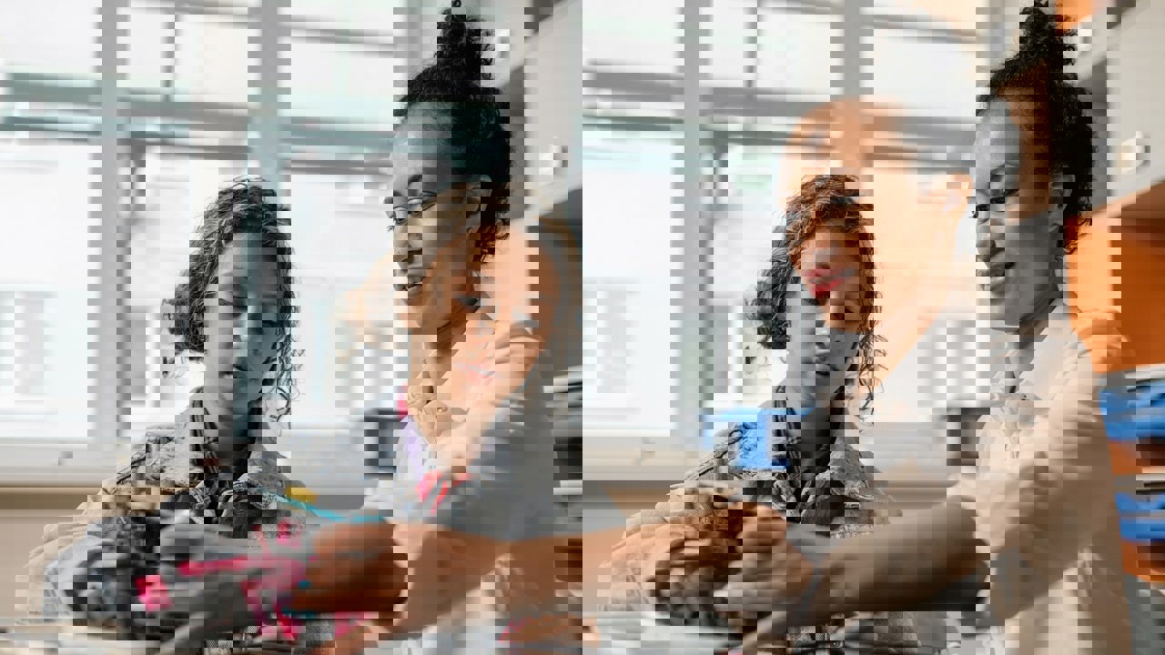 Teacher working with a student on a Lego robotics kit in a school classroom